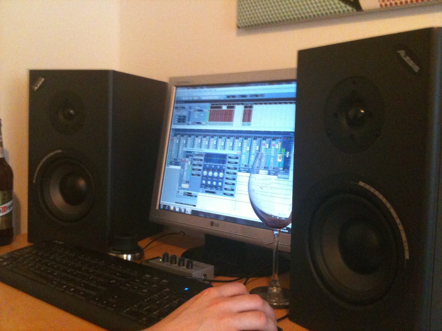 A darkened studio desk with large monitor speakers and a hand on the mouse