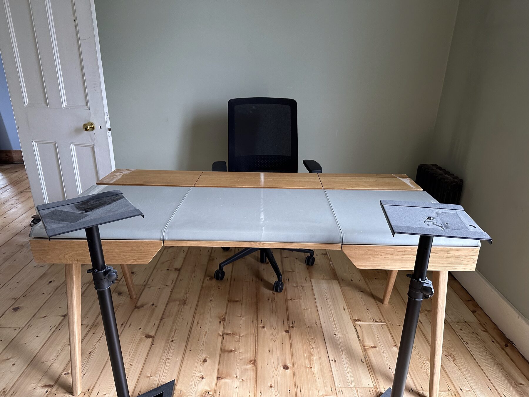 A purpose-built white desk on a standing frame flanked by two monitor speakers