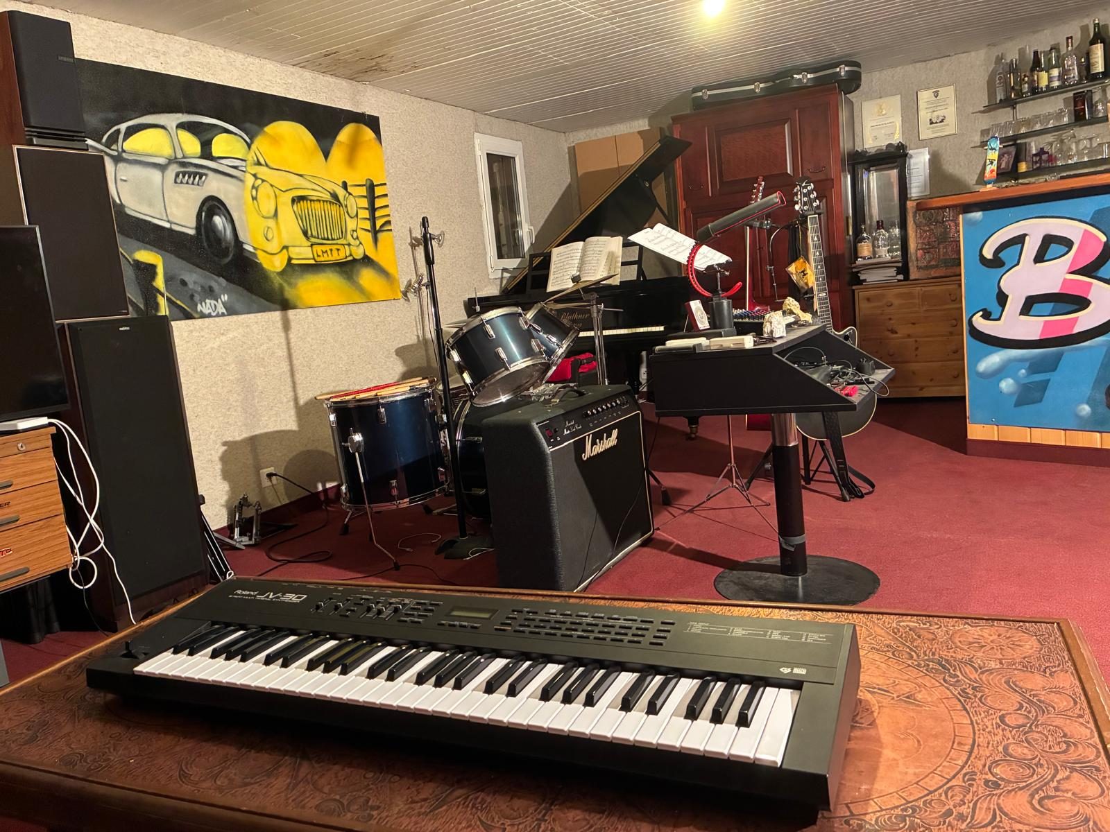 Jean Marie's basement studio in Les Diablerets, Switzerland: a yellow car mural, drum kit, grand piano, synthesiser and guitars